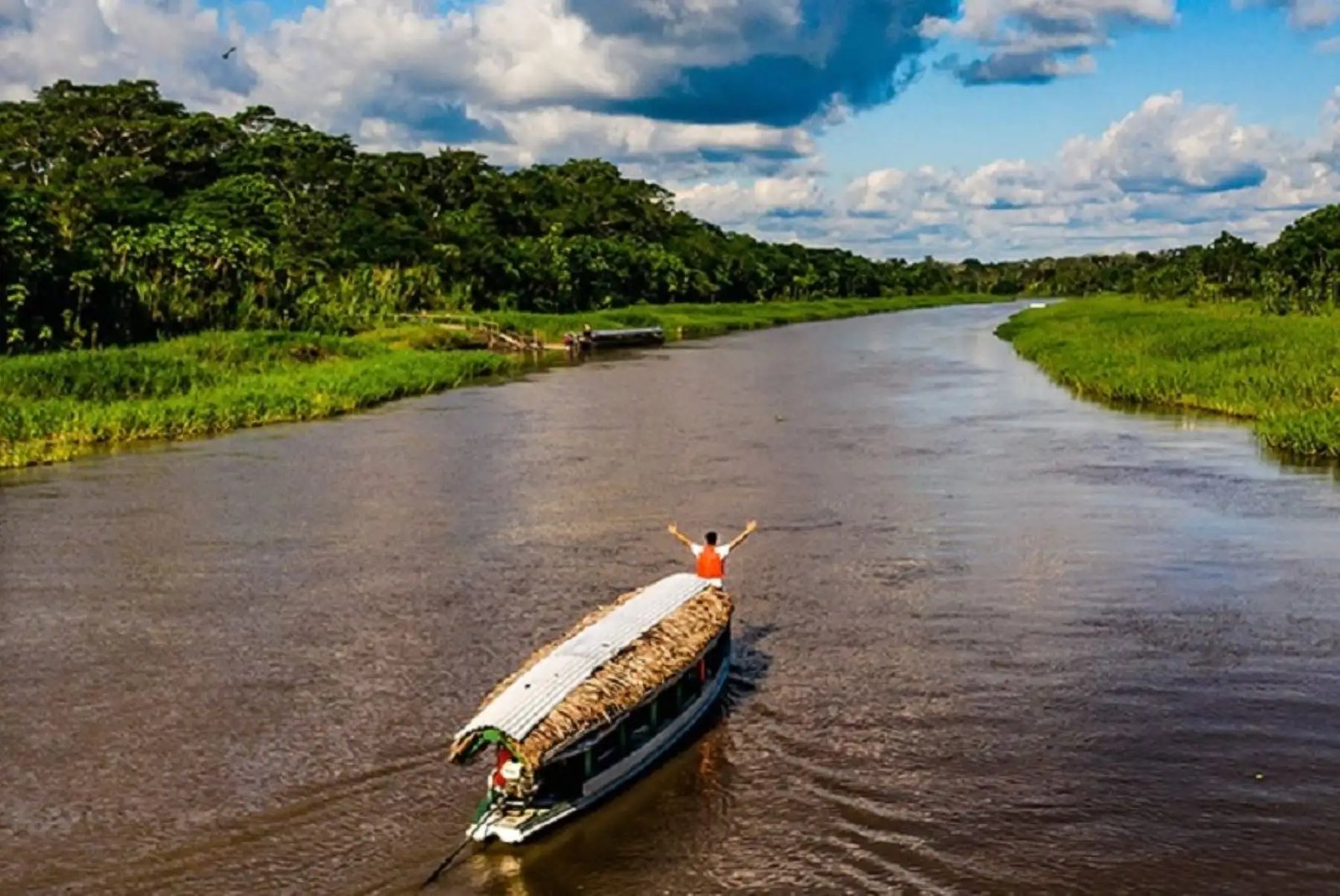 A boat on an Amazon river beneath a dramatic sky