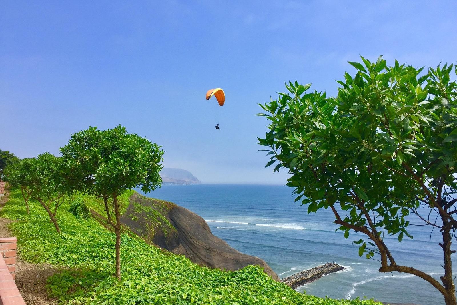 A paraglider over the Miraflores cliffs above the Pacific